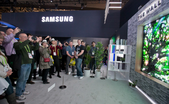 지난해 열린 CES 2018 기간에 미국 라스베이거스 컨벤션 센터의 삼성전자 부스에 전시한 세계 최초 모듈러 TV '더 월'(왼쪽 사진). CES 2018 기간에 미국 라스베이거스 컨벤션 센터 LG전자 부스에 전시한 올레드 협곡.  삼성전자·CTA 제공